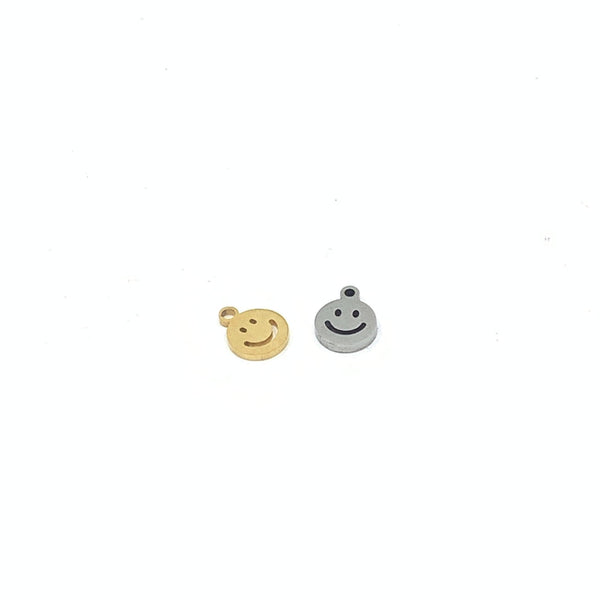 Gold and steel colored little smiley face charms against a white background
